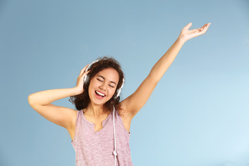 Fototapeta na wymiar African American woman listening to music in headphones on grey background