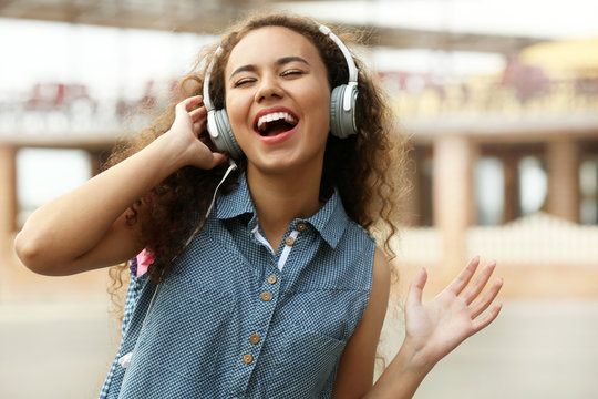 African American woman listening to music in headphones in the street