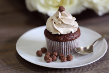 Tasty cupcake with roses on wooden table