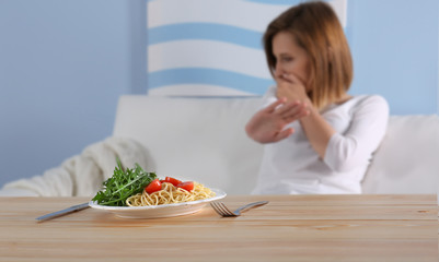 Young depressed girl with eating disorder at wooden table