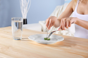 Young depressed girl with eating disorder at wooden table
