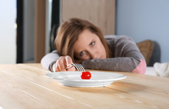 Young depressed girl with eating disorder at wooden table