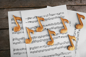 Golden music notes and sheets on wooden table, top view