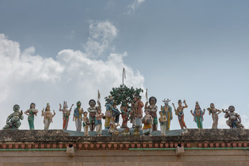 Chettinad, India - October 17, 2013: Row of statues shows the wedding of Shiva with Meenakshi and plenty of guests such as Vishnu, Ayyanar and Hayagriva. Against blue sky.