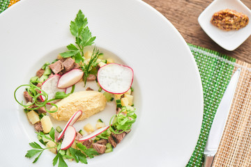 Top view of the blank for okroshka with beef in white plate on wooden table