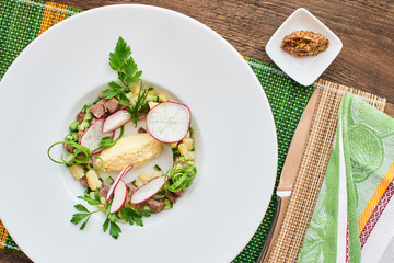Top view of the blank for okroshka with beef in white plate on wooden table