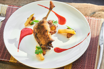 Breakfast of duck legs confit with caramelized Apple and potato served on a white plate