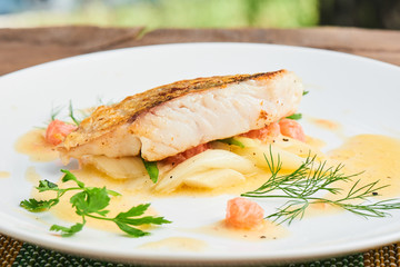 Pike perch fillet with leeks and beurre Blanc served in a white plate