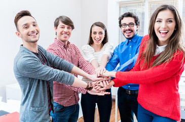 Studenten in Hochschule halten zusammen und stapeln Hände als Team