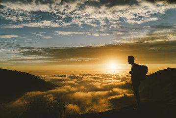 Silhouette male hiker standing on mountain during sunset