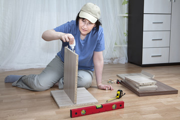 Furniture assembly, woman lubricates surface of adhesive chipboa