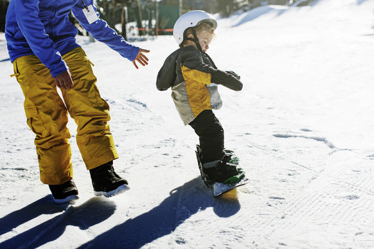 Father helping boy to learn ski