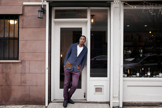 Portrait of young man leaning against door while standing outdoors
