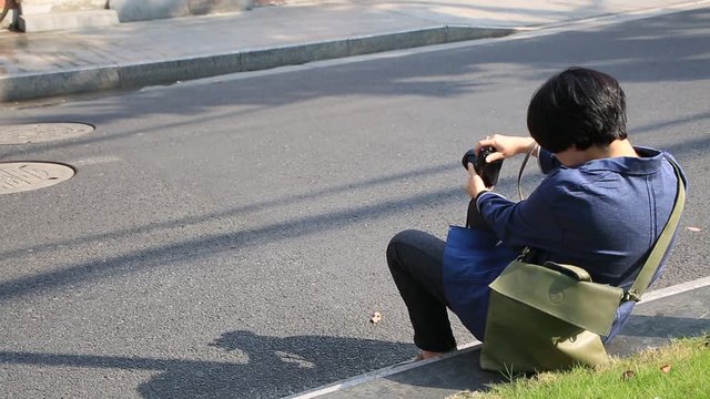 Asian woman taking pictures of traditional chinese architecture with a camera in Shanghai, China 