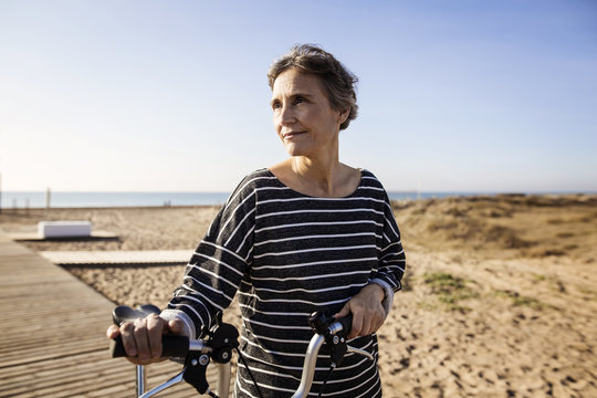 Woman holding bicycle while standing on boardwalk