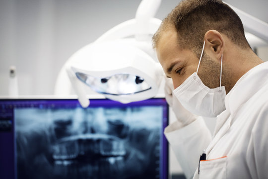 Male dentist adjusting lamp against x-ray in clinic