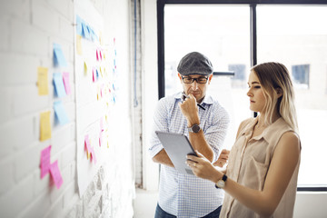 Businesswoman showing tablet computer to male colleague at creative office