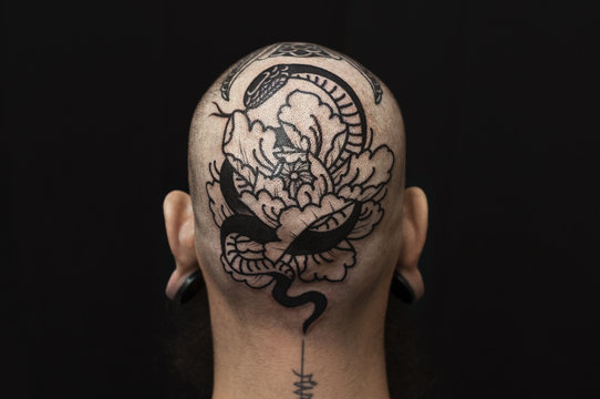 Black ink snake tattoo on man's head