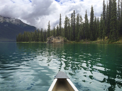 Bow of canoe on lake under cloudy sky