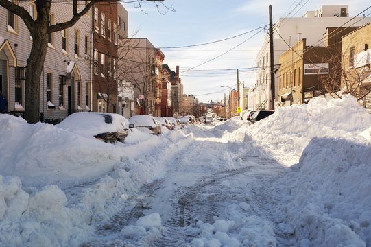 Cars on snow covered road amidst buildings in city