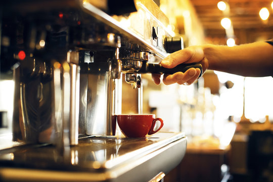 Cropped hand holding portafilter on coffee machine