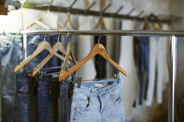 Various jeans hanging on coathangers at workshop