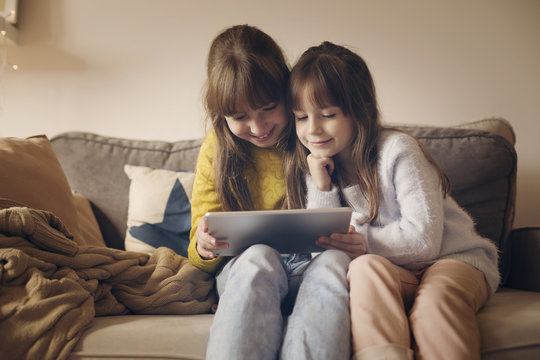 Sisters Using Tablet Computer While Sitting At Home