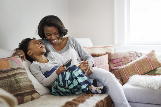 Happy mother and son using digital tablet while sitting on sofa at home