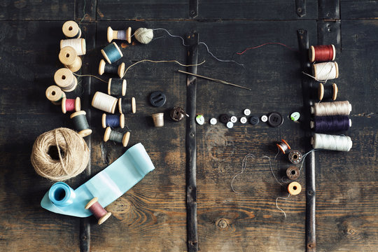 Overhead view of sewing equipment with thread reels on wooden table