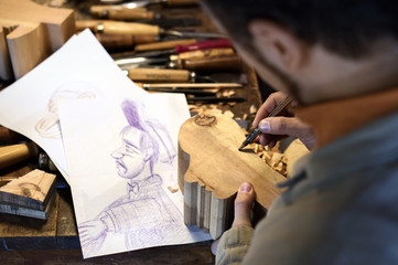 High angle view of craftsman drawing on sculpture in workshop