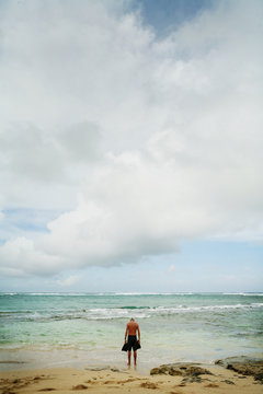Full length of man standing on seashore against cloudy sky