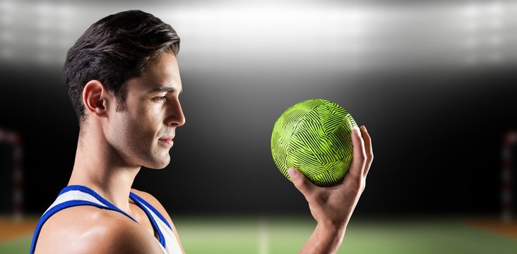 Confident athlete man holding a ball  against digital image of handball field indoor
