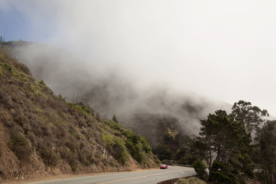Car moving on mountain road during foggy weather