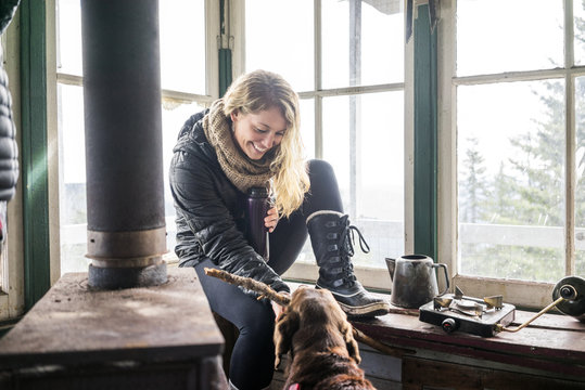 Happy Woman Playing With Dog In Cottage