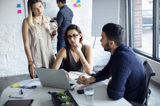 Business people using laptop while discussing in office