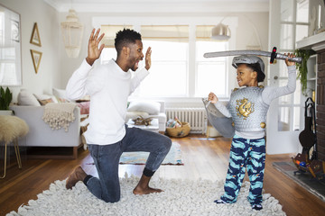 Father and son playing with sword at home