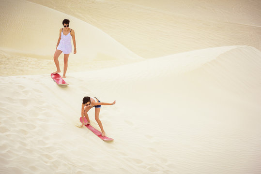 High angle view of sisters sandboarding in desert
