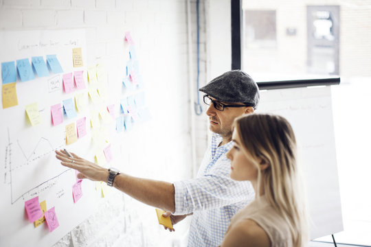 Businessman explaining strategy to female colleague at creative office