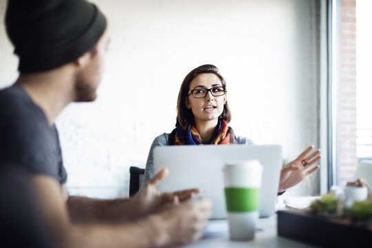 Businesswoman Explaining To Colleague During Meeting In Office