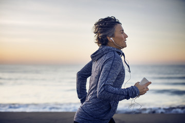 Woman running and listening to music on beach