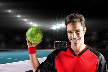 Portrait of happy athlete man holding a ball  against handball field indoor 