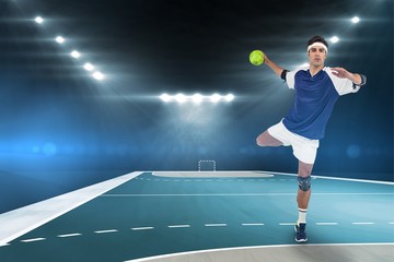 Portrait of sportsman throwing a ball against handball field indoor 
