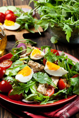 Fresh salad with chicken, tomatoes, eggs and arugula on plate