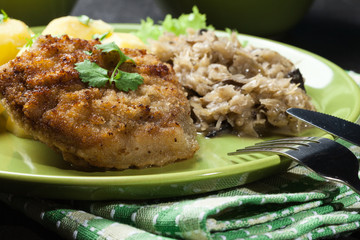 Fried pork schnitzel served with boiled potatoes and fried sauer