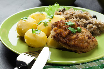 Fried pork schnitzel served with boiled potatoes and fried sauer