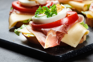 Delicious sandwich with prosciutto ham, cheese, tomato and egg