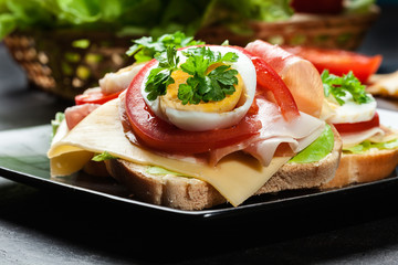 Delicious sandwich with prosciutto ham, cheese, tomato and egg