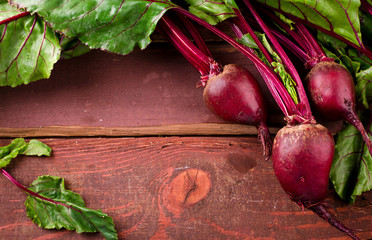 Organic young beets with green leaves on wooden table