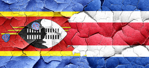 Swaziland flag with Costa Rica flag on a grunge cracked wall
