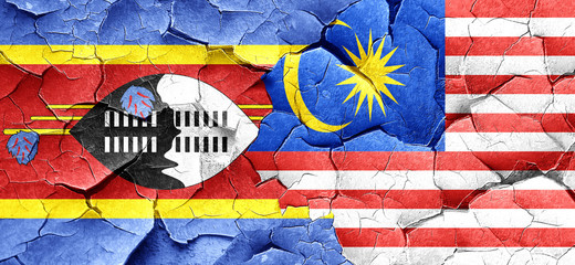 Swaziland flag with Malaysia flag on a grunge cracked wall